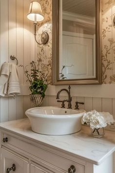 a bathroom sink sitting under a mirror next to a white counter top with flowers on it