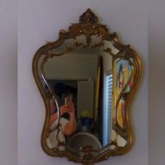 a woman taking a selfie in front of a gold framed mirror on the wall