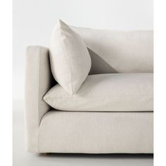 a white couch with two pillows on it's back and one pillow in the middle