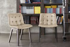 two chairs sitting next to each other in front of a book shelf