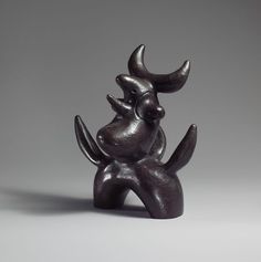 a black sculpture sitting on top of a white table next to a gray wall and floor