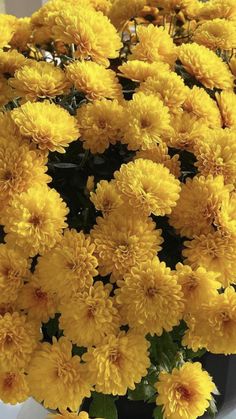 yellow flowers are in a black vase on the table