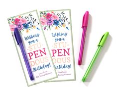 two pen pens sitting next to each other on top of a white table with pink and blue flowers