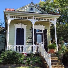 a white house with black shutters on the front porch and steps leading up to it