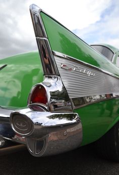 the back end of an old green car with chrome trim and tail fins on it