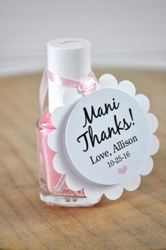 a small bottle filled with pink liquid sitting on top of a wooden table next to a tag