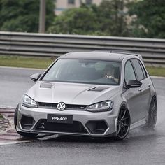 a silver car driving down a wet road