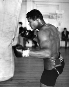 a man in shorts and boxing gloves standing next to a punching bag