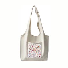 a white bag with an embroidered design on the front and side pocket, featuring flowers