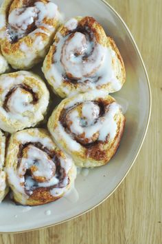 several cinnamon rolls on a plate with icing drizzled over the top