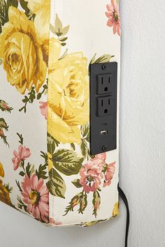 an electrical outlet is plugged in to a floral wallpapered light switch box