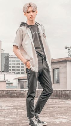 a young man standing on top of a cement floor next to a tall building with buildings in the background