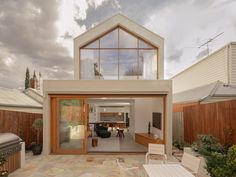 an outdoor living area with patio furniture and large glass windows on the side of the house