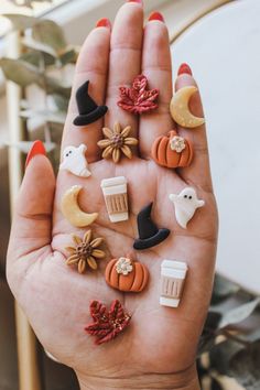 a person's hand with various miniature items on it, including pumpkins and witches