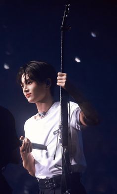 a male in a white shirt and black pants with a microphone on his shoulder at a concert