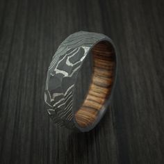 This 7mm Damascus Steel ring has a ROCK ACID finish and features a full WALNUT WOOD interior sleeve. Each ring is custom made and the pattern unique so no two rings are exactly the same. Damascus Steel rings are very desirable. You ring comes with a COMFORT-FIT for extra satisfaction. Our DAMASCUS ring WILL NOT RUST OR TARNISH. Damascus steel is an ancient art form. This blacksmith alloy is made using two types of Surgical and Fine Stainless steel that are layered in 100 alternating layer and th Men Wedding Rings, Rock Ring, Cushion Moissanite Engagement Ring, Branch Engagement Ring, Damascus Ring, Wooden Wedding Ring, Damascus Steel Ring, Leaf Engagement Ring, Men Rings