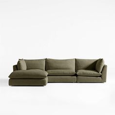 a large sectional couch with pillows on the top and bottom, sitting in front of a white wall