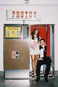 a man and woman posing in front of a photo booth