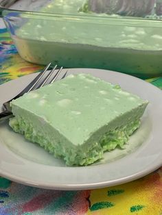 a piece of lime jello salad on a white plate with a fork next to it