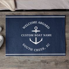 a welcome aboard mat with an anchor and name on it next to shoes, sneakers and towel