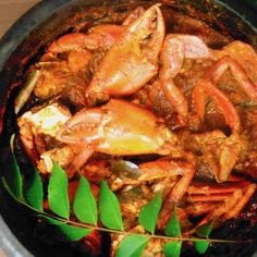 cooked crabs and other seafood are in a pot with green leaves on the side, ready to be eaten