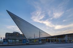 a large triangular shaped building sitting on the side of a road next to a train station