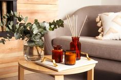 a table with candles and vases on it in front of a couch, next to a coffee table