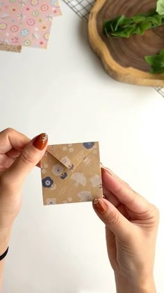 a woman holding up a piece of paper with an animal pattern on it, next to a plant