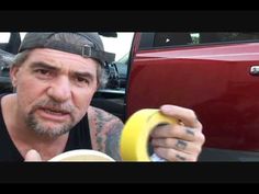 a man holding a banana in front of a red car with his hand on the steering wheel