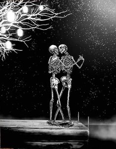 two skeletons standing next to each other in front of a tree with lights on it