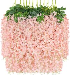 pink flowers are hanging from the side of a planter filled with green leaves and greenery