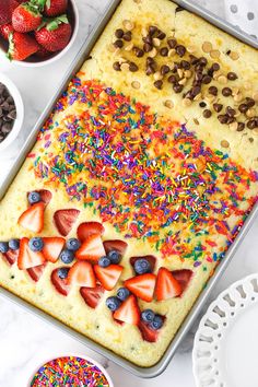 a sheet cake with strawberries, chocolate chips and sprinkles on it