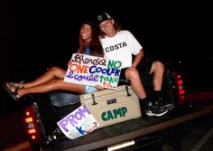 a man and woman sitting on the back of a pick up truck holding signs that read camp