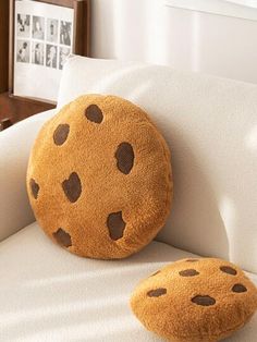 a stuffed cookie pillow sitting on top of a white couch next to a wooden frame