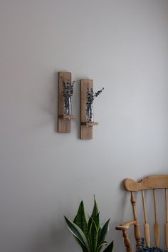 two wooden sconces mounted on the wall above a chair with a potted plant