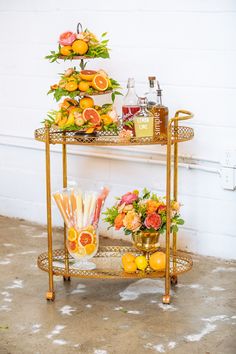 two tiered serving trays with drinks and flowers on them, one is gold