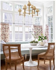 a dining room table with four chairs and a vase on the table in front of it