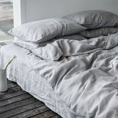 an unmade bed sitting on top of a wooden floor next to a white wall