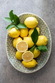 a bowl filled with lemons and green leaves