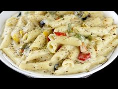 a white bowl filled with pasta covered in cheese and vegetables on top of a black table