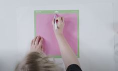 a person writing on a piece of pink paper