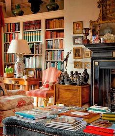 a living room filled with lots of books on top of a wooden table next to a fire place