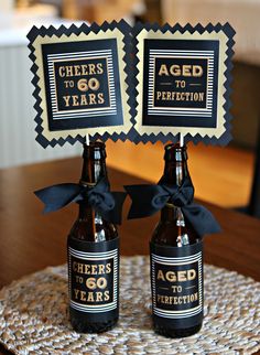 two beer bottles sitting on top of a table next to each other with black ribbon