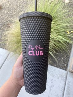 a person holding up a cup with a sticker on it that says don't mess club