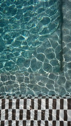 an empty swimming pool with clear water and checkerboard flooring in the foreground