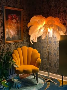 a yellow chair sitting in front of a lamp next to a painting on the wall