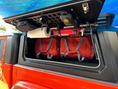 the back end of a red truck with luggage in it's trunk and an awning