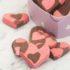 heart shaped chocolates in a pink box on a white counter top with hearts cut out of them