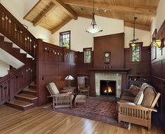 a living room filled with furniture and a fire place next to a stair case on top of a hard wood floor