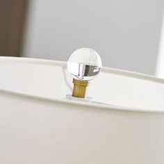 a close up of a light fixture on a white lamp shade with a metal ball in the center